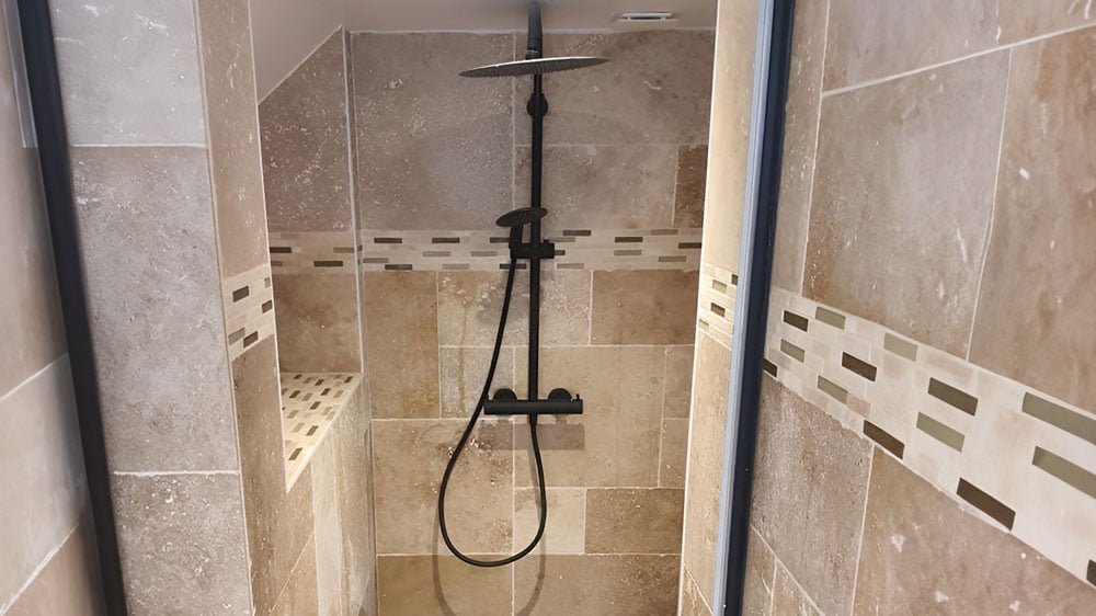 Douche moderne avec carrelage beige et pommeau de douche noir mat.